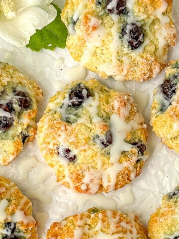 Blueberry muffin tops with vanilla glaze on parchment paper.