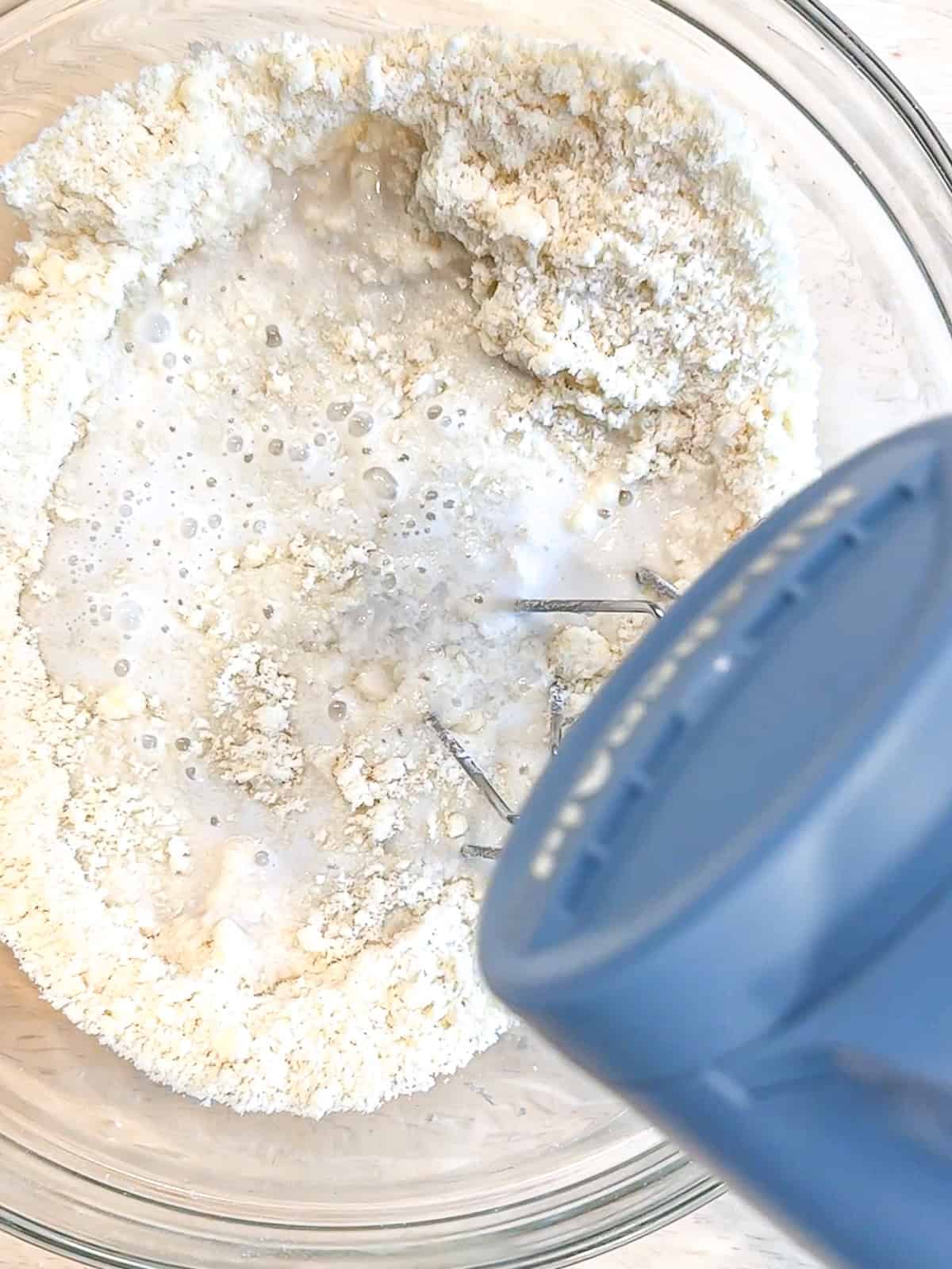 Mixing dry ingredients and coconut milk to make coconut cake.