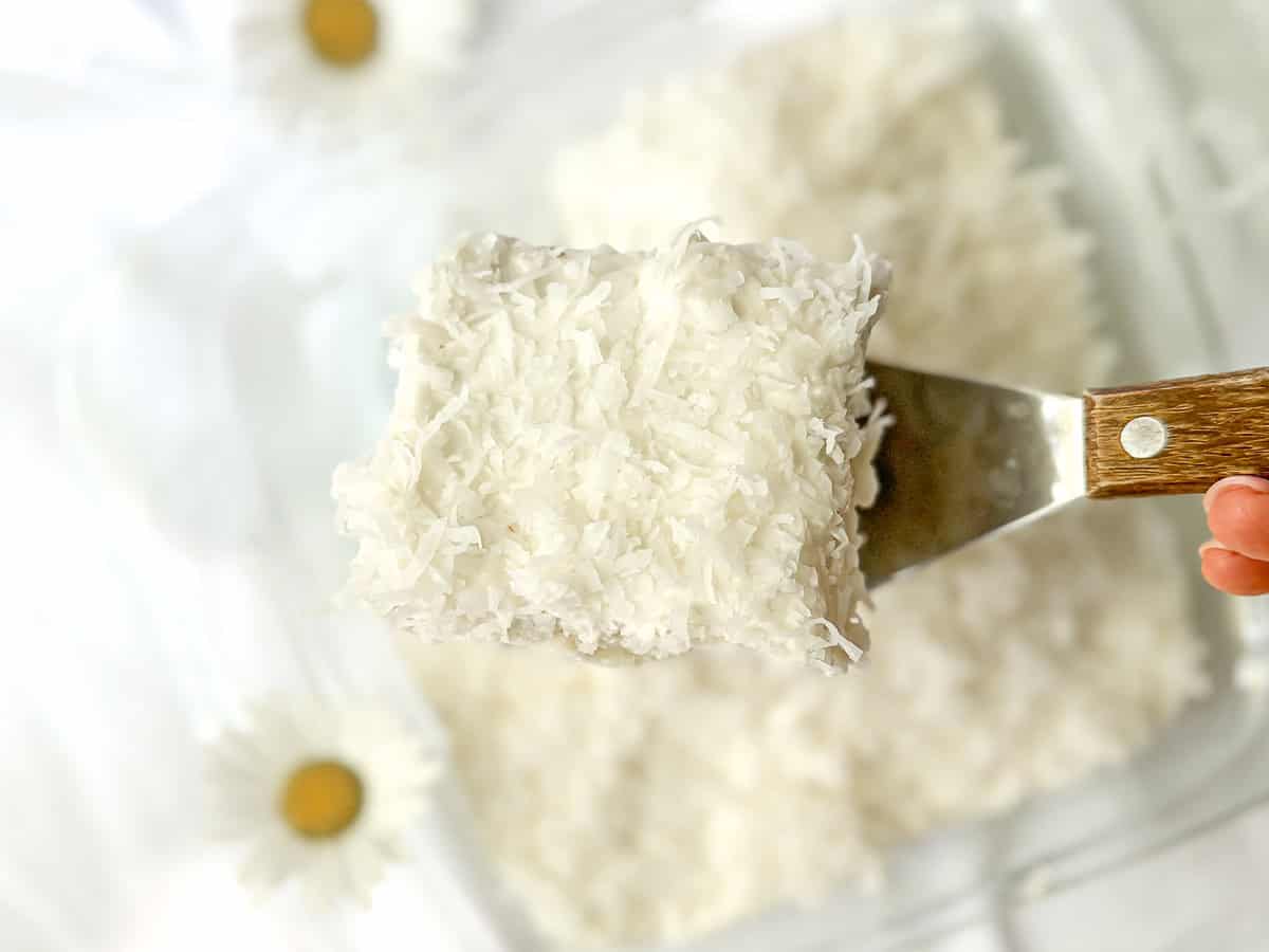 A spatula lifting a slice of coconut cake.