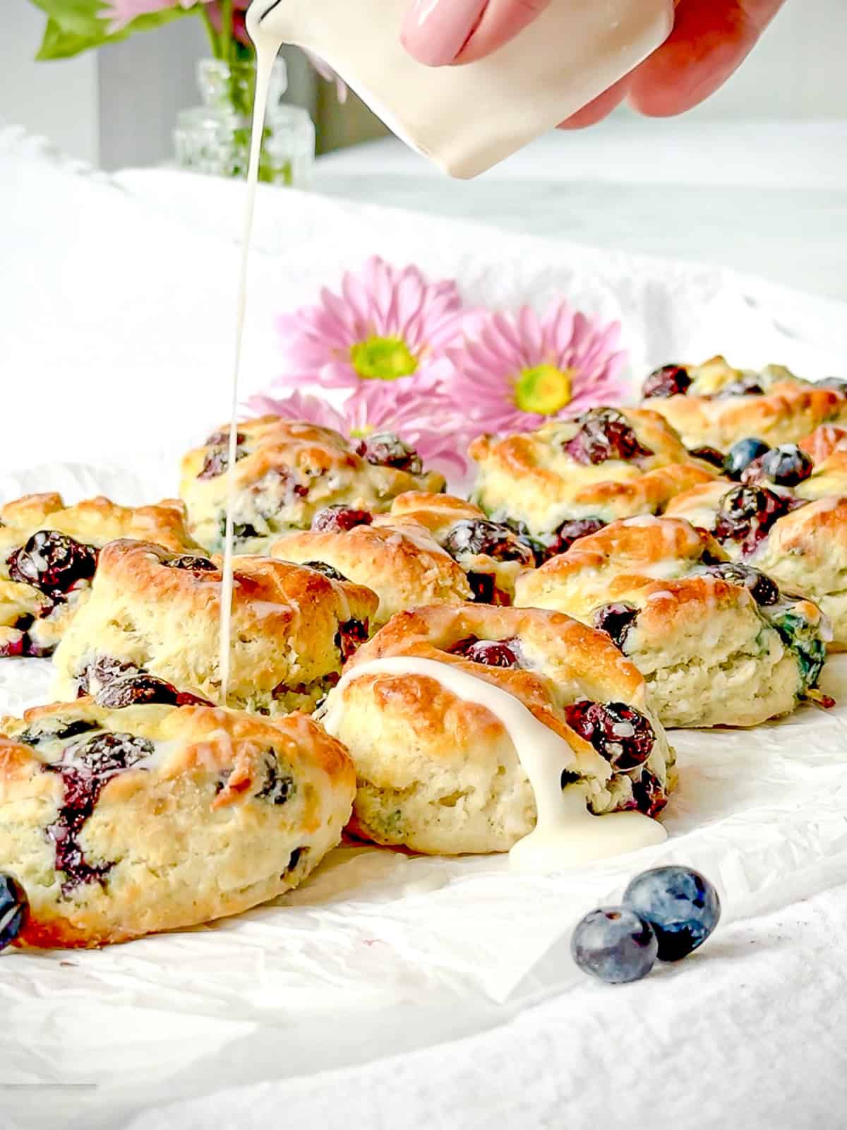 Drizzling lemon glaze over blueberry biscuits.