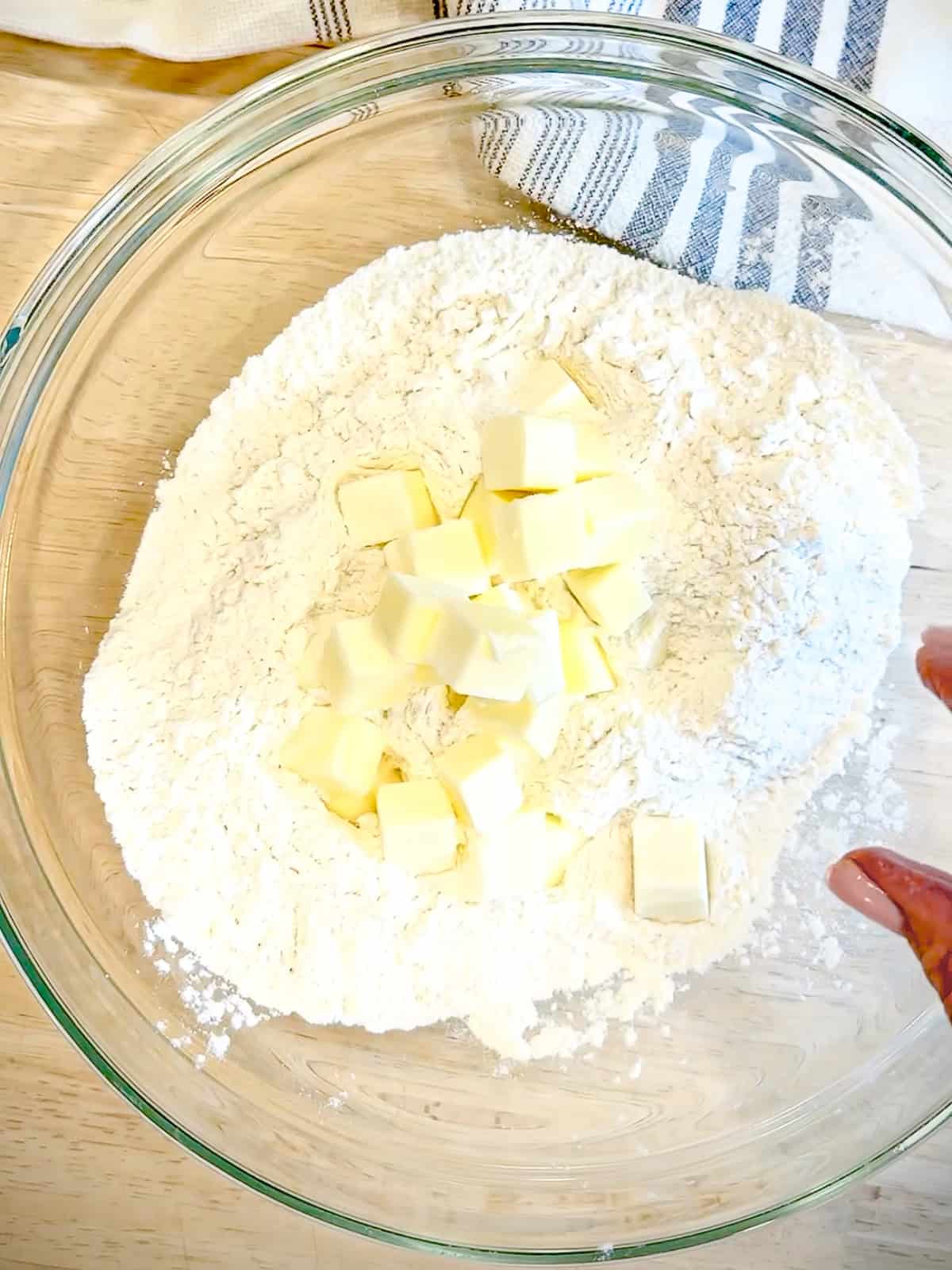 Adding butter to dry ingredients for biscuits.