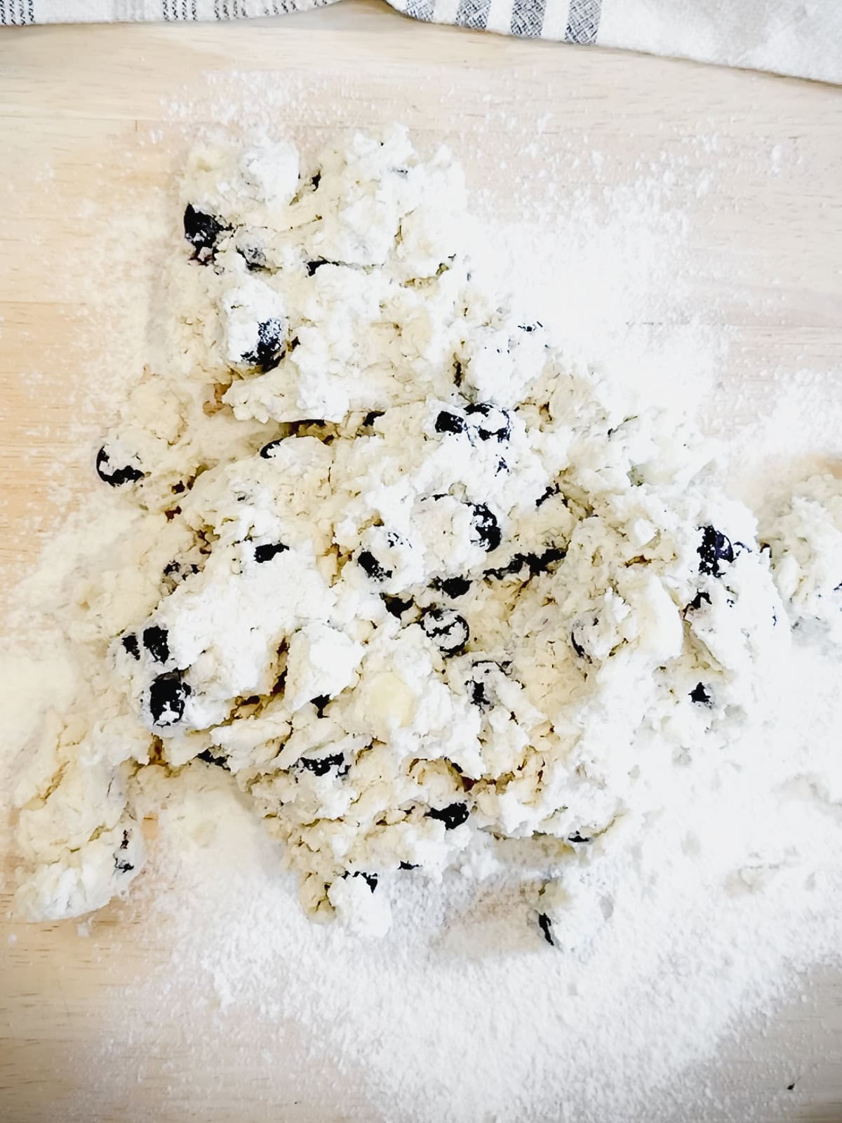 Blueberry biscuit dough on wooden counter.