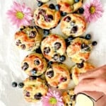 Pouring lemon glaze on glazed blueberry biscuits.