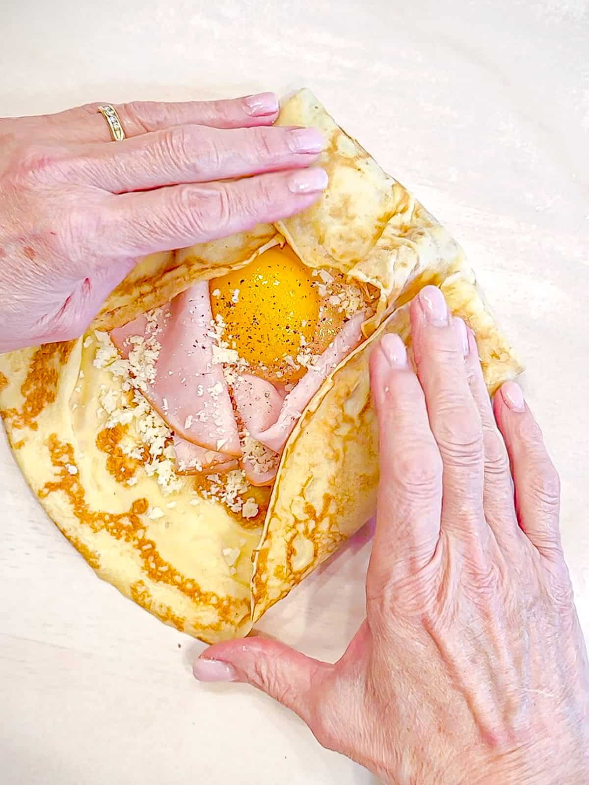 Folding crepes over ham, egg, and cheese.