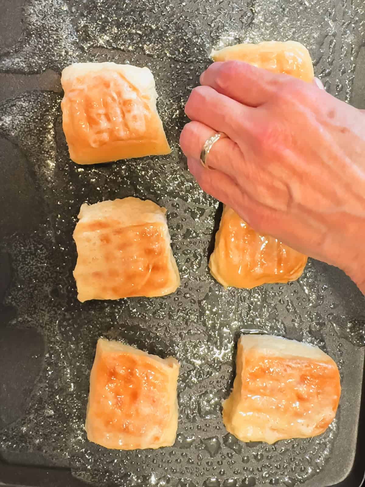 Placing Hawaiian bread, French toast on a griddle to cook.