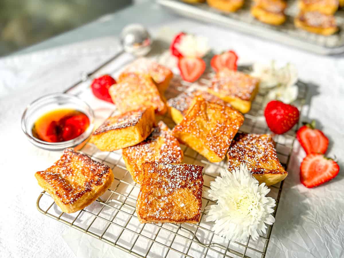 Hawaiian bread French toast with sliced strawberries on a wire rack .