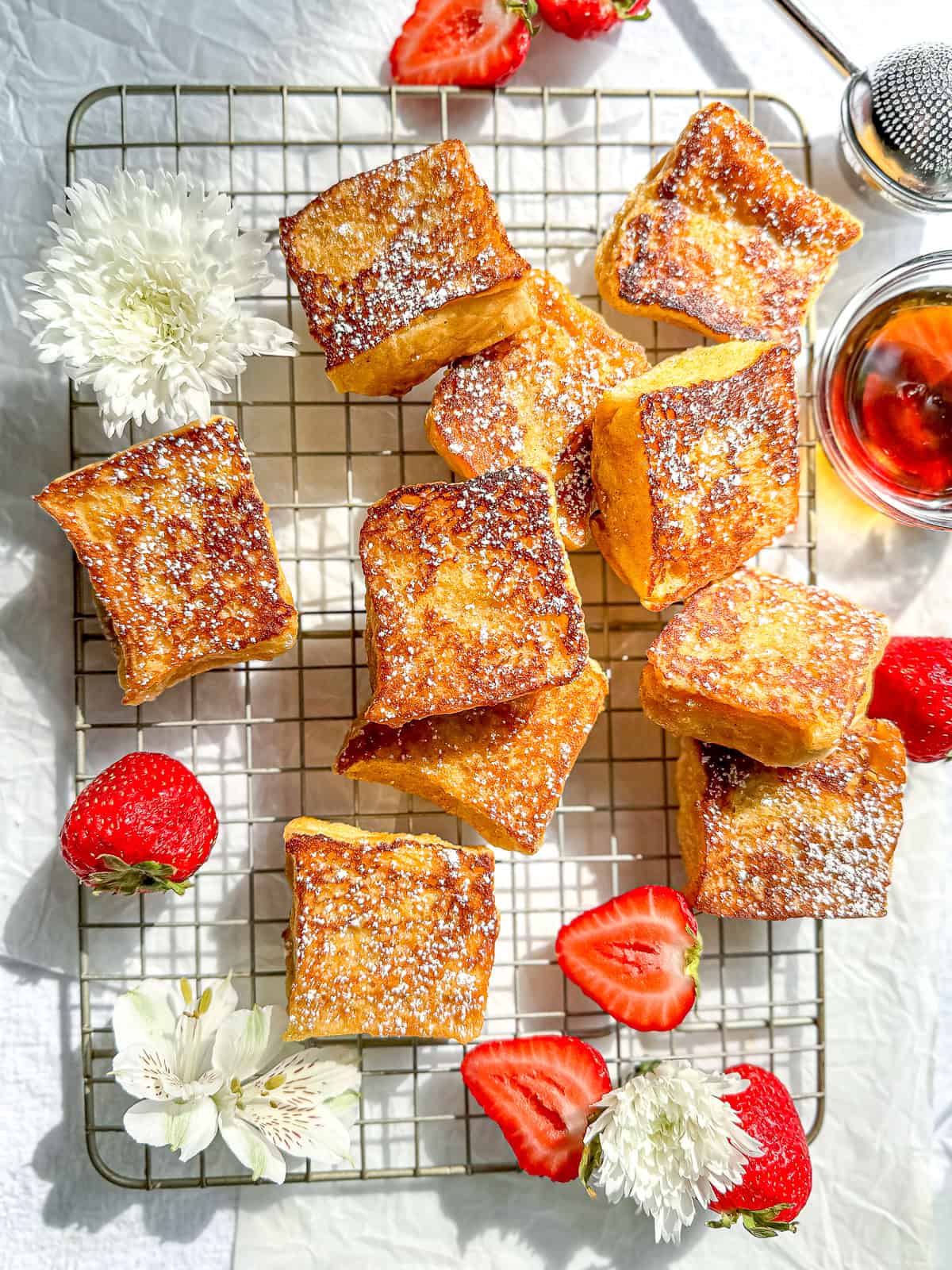 Hawaiian bread French toast with sliced strawberries on a wire rack .