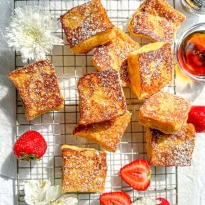 Hawaiian bread French toast with sliced strawberries on a wire rack .