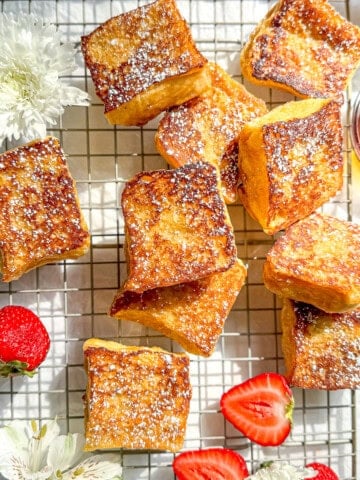 Hawaiian bread French toast with sliced strawberries on a wire rack .