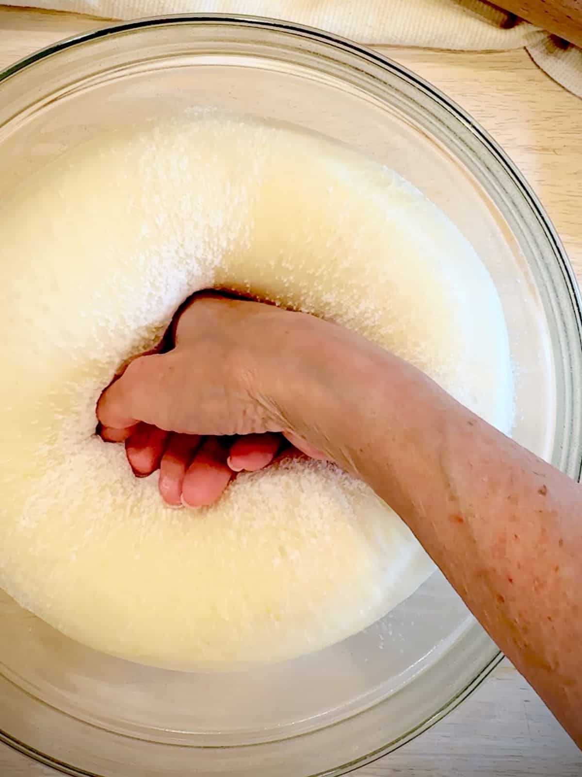 Punching down fully risen brioche dough.