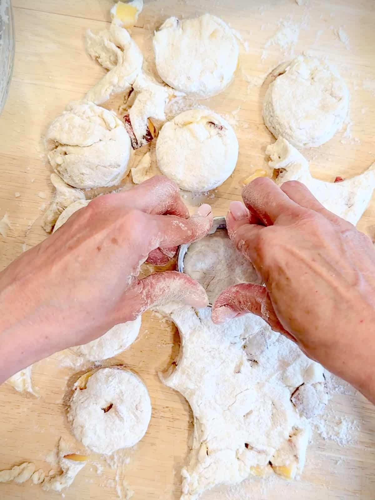 Using a biscuit cutter to cut out peach biscuits.