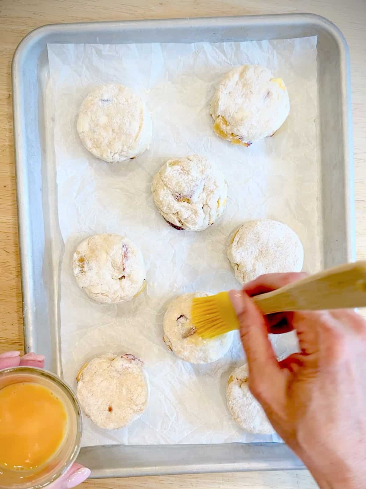 Brushing peach Biscuits with an egg wash.