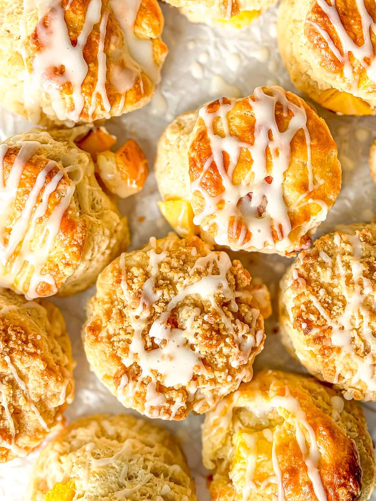 Peach Biscuits with vanilla drizzle on parchment paper.