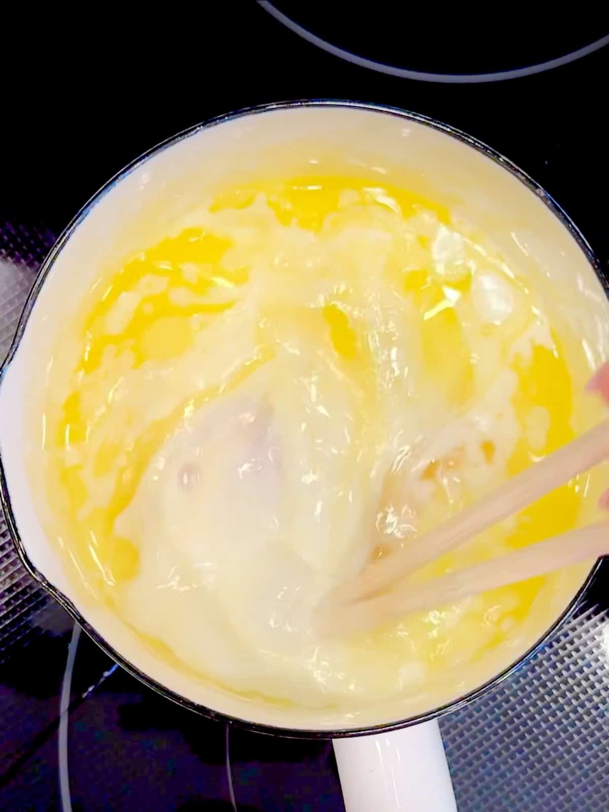 Whisking milk and egg into melted butter.