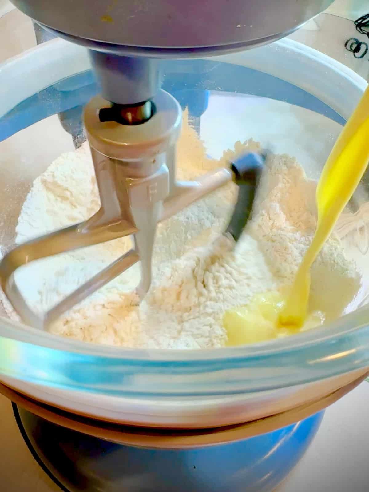 Pouring wet ingredients into dry ingredients in a stand mixer.