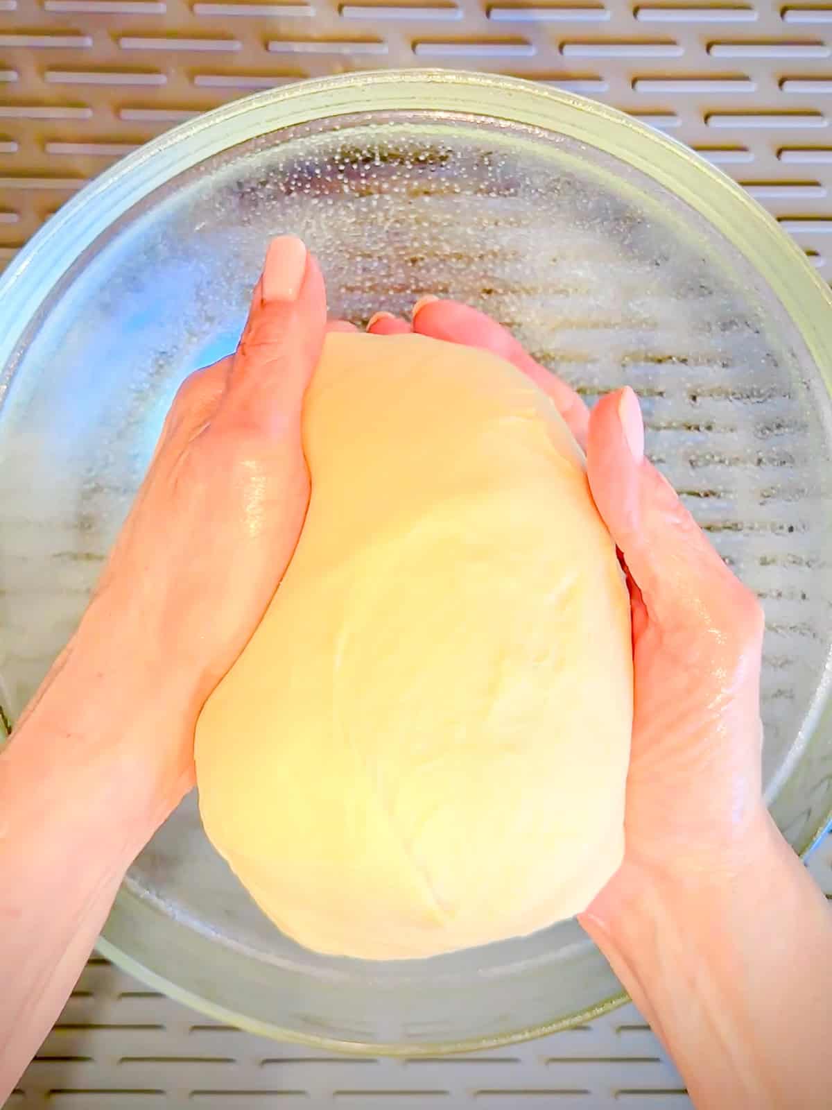 Placing kneaded dough in a greased bowl.