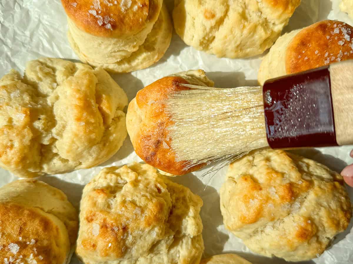 Brushing melted butter on top of two ingredient biscuits.