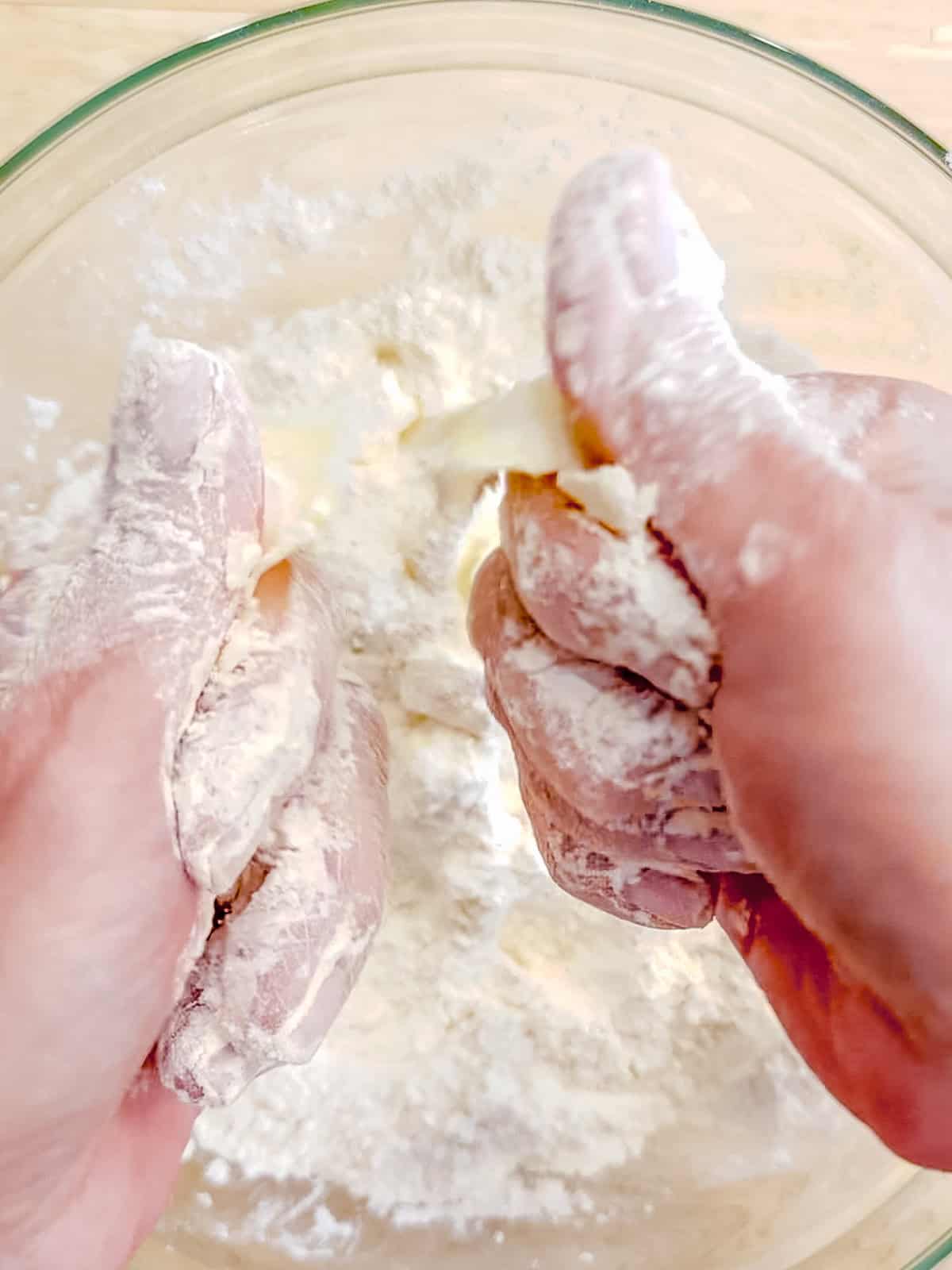 Using fingers to cut butter cubes into self rising flour.