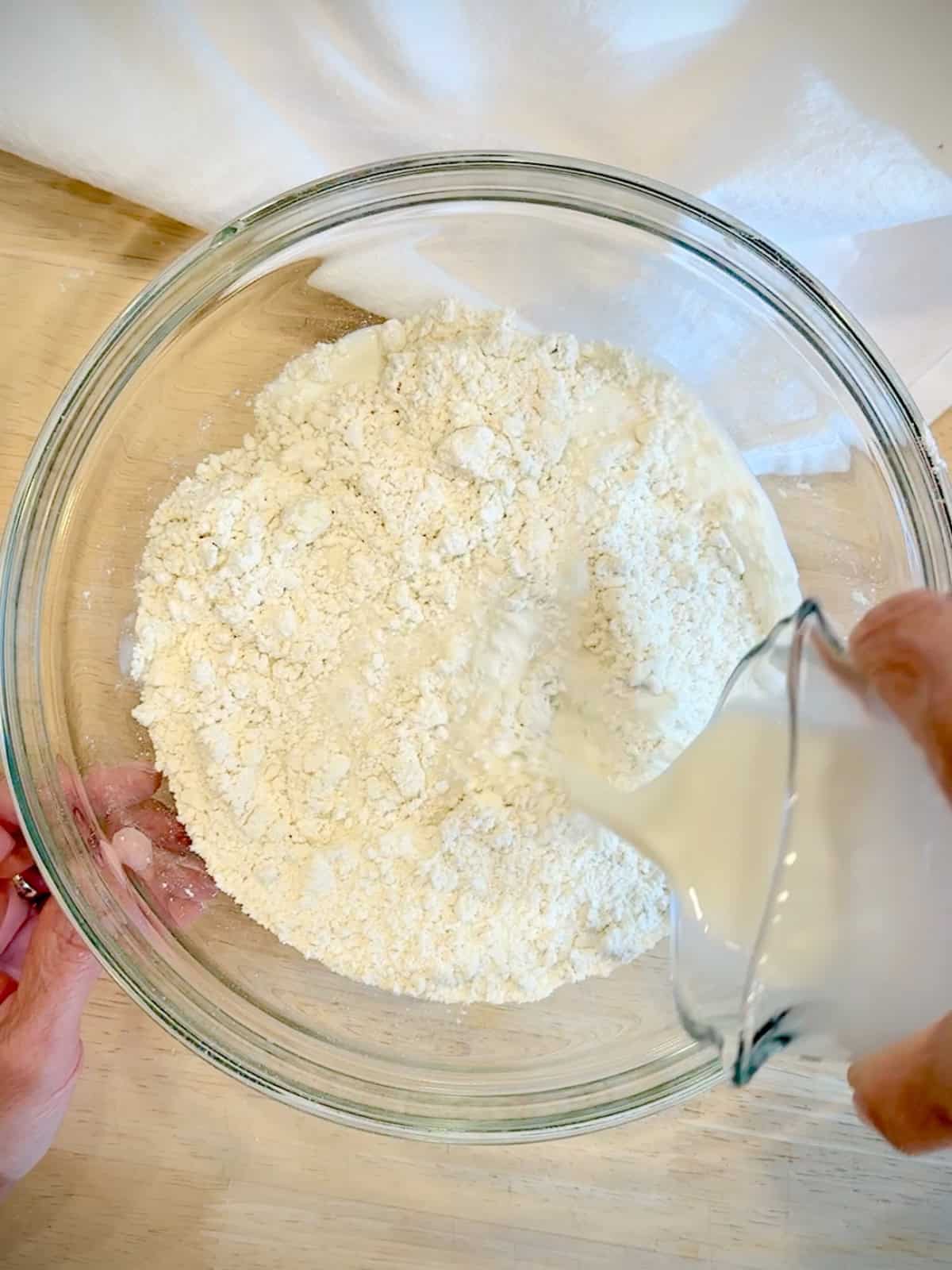 Pouring whole milk into self rising flour and butter mixture.