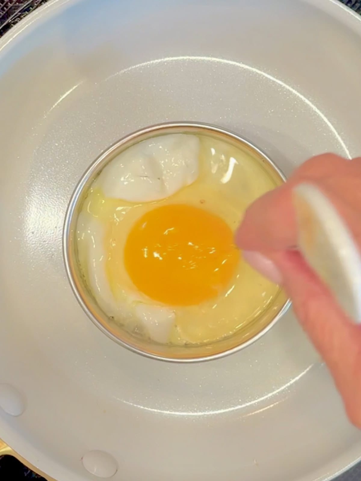 Poking the yolk of an frying egg with a skewer.