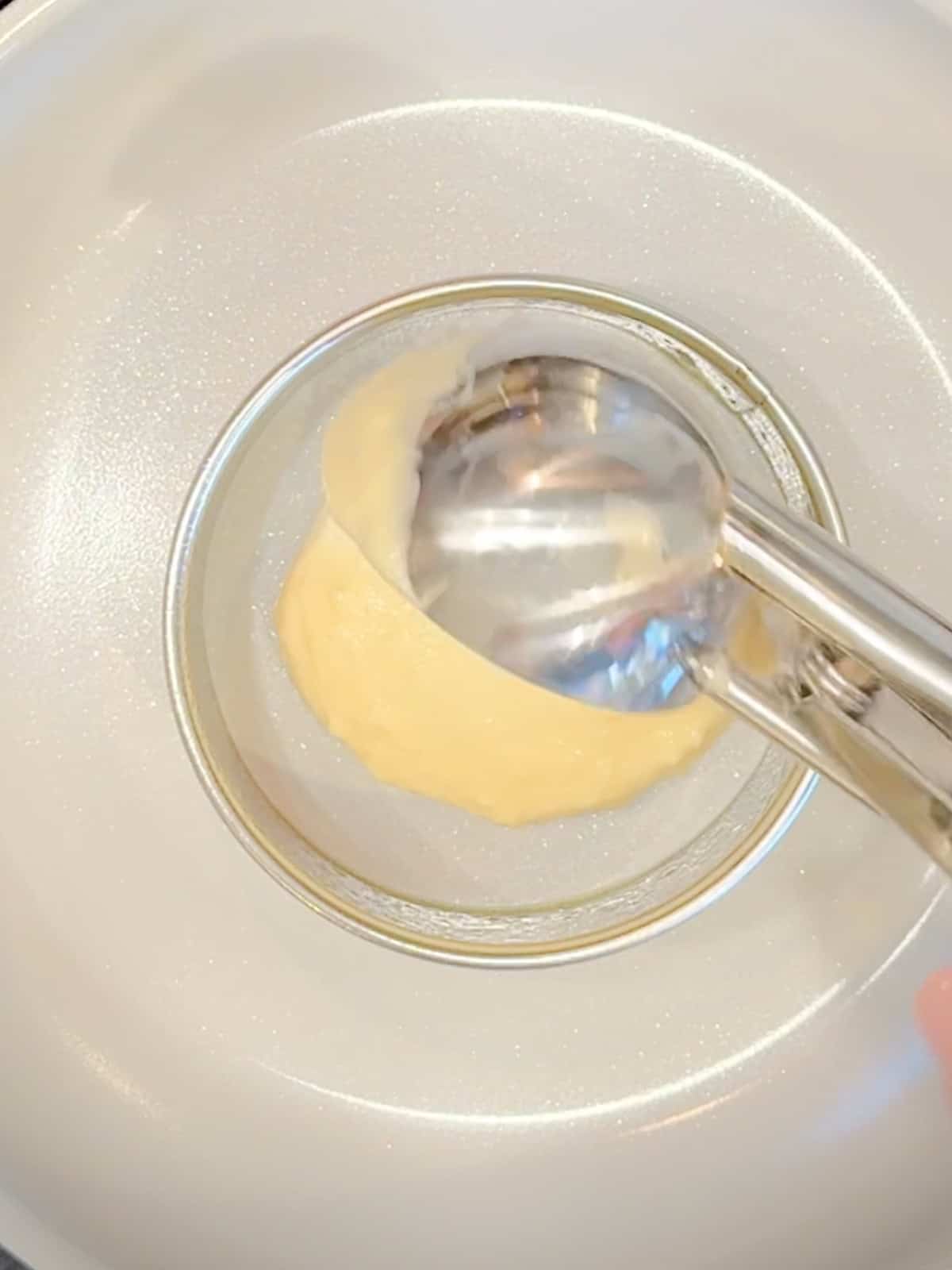 Scooping pancake batter into a ring, mold to make homemade Mcgriddles.