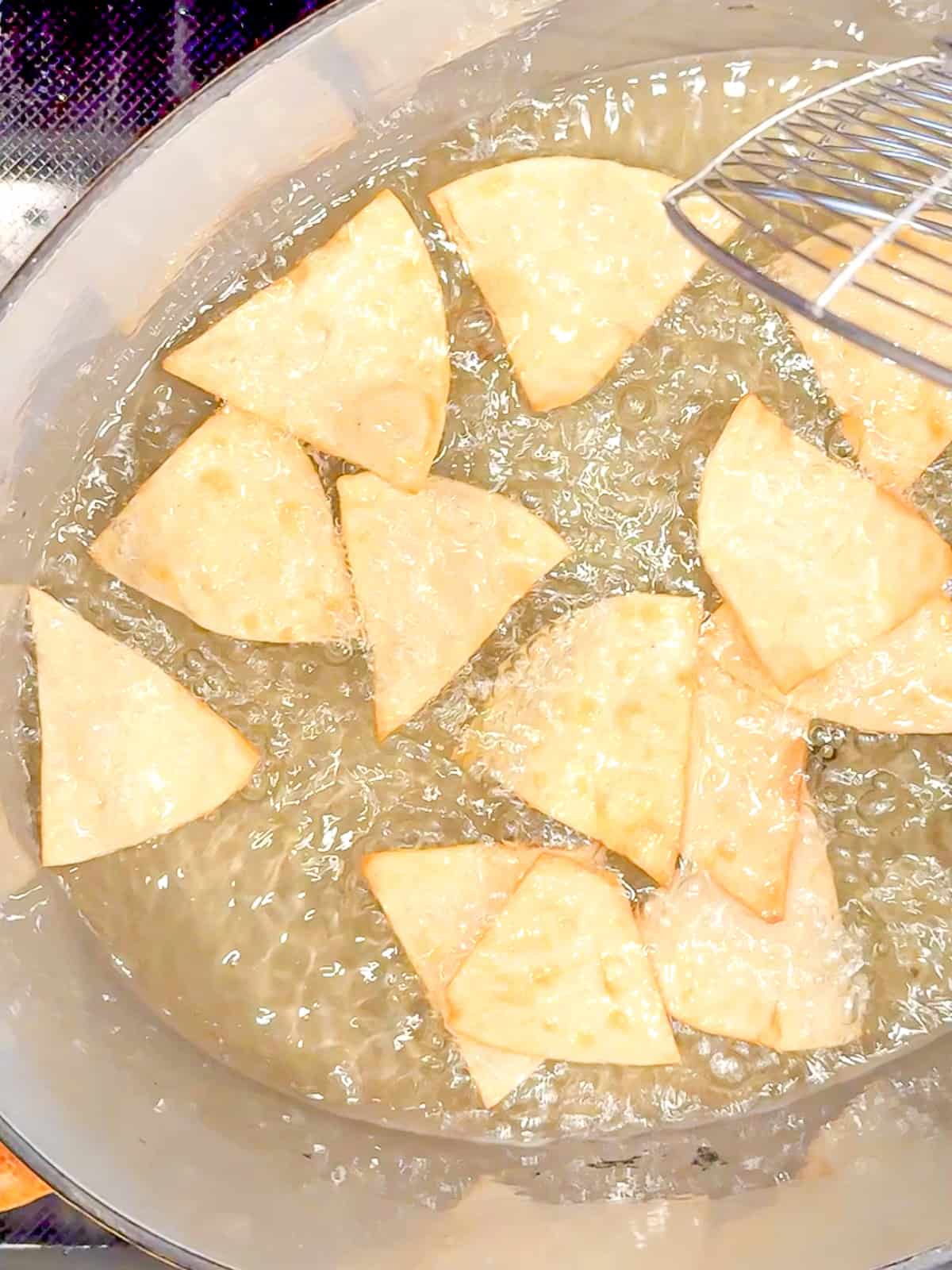 Cooking tortilla chips in hot oil.