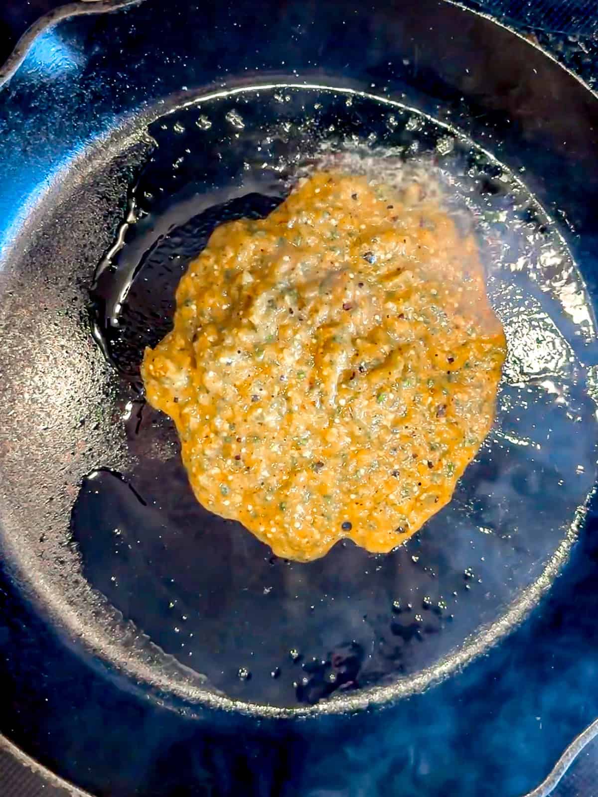 Adding tomatillo salsa to a hot cast-iron pan.