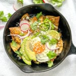 Breakfast Chilaquiles Verde in a cast-iron pan with an egg on it.