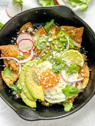 Breakfast Chilaquiles Verde in a cast-iron pan with an egg on it.