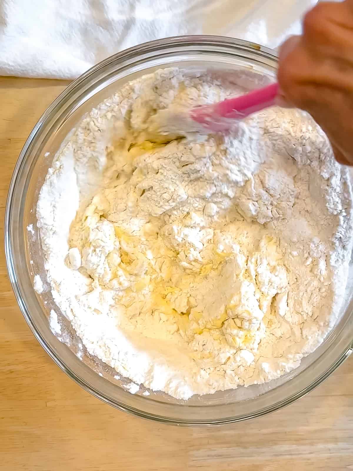 Mixing muffin batter in a glass bowl.