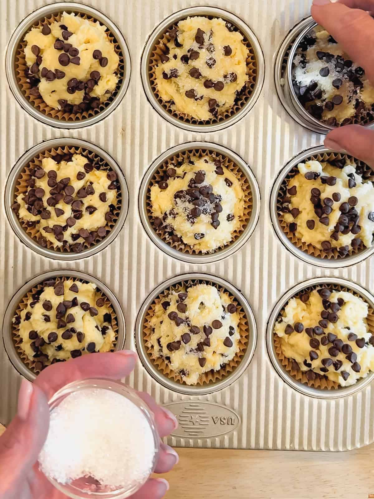 Adding sparkling sugar to the top of chocolate chip muffins.