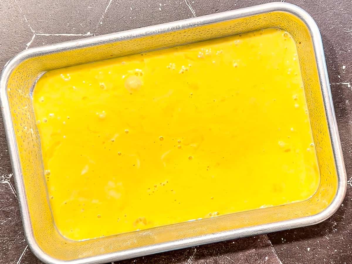 Uncooked eggs in a small sheet pan.