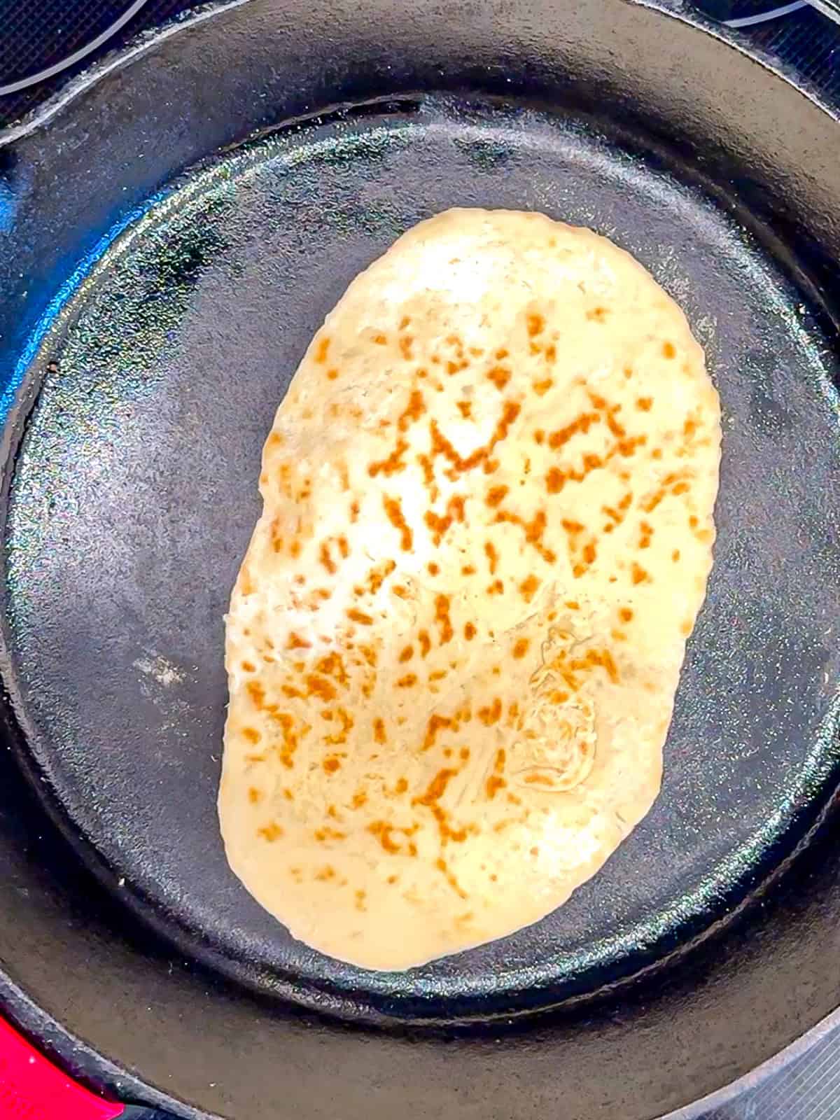 Cooking a two ingredient flatbread in a cast-iron pan.