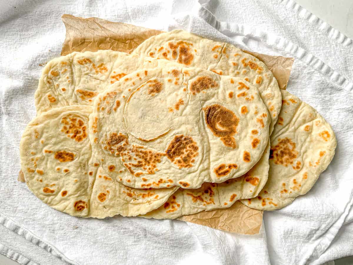 Horizontal picture of two ingredient flatbreads on parchment paper.