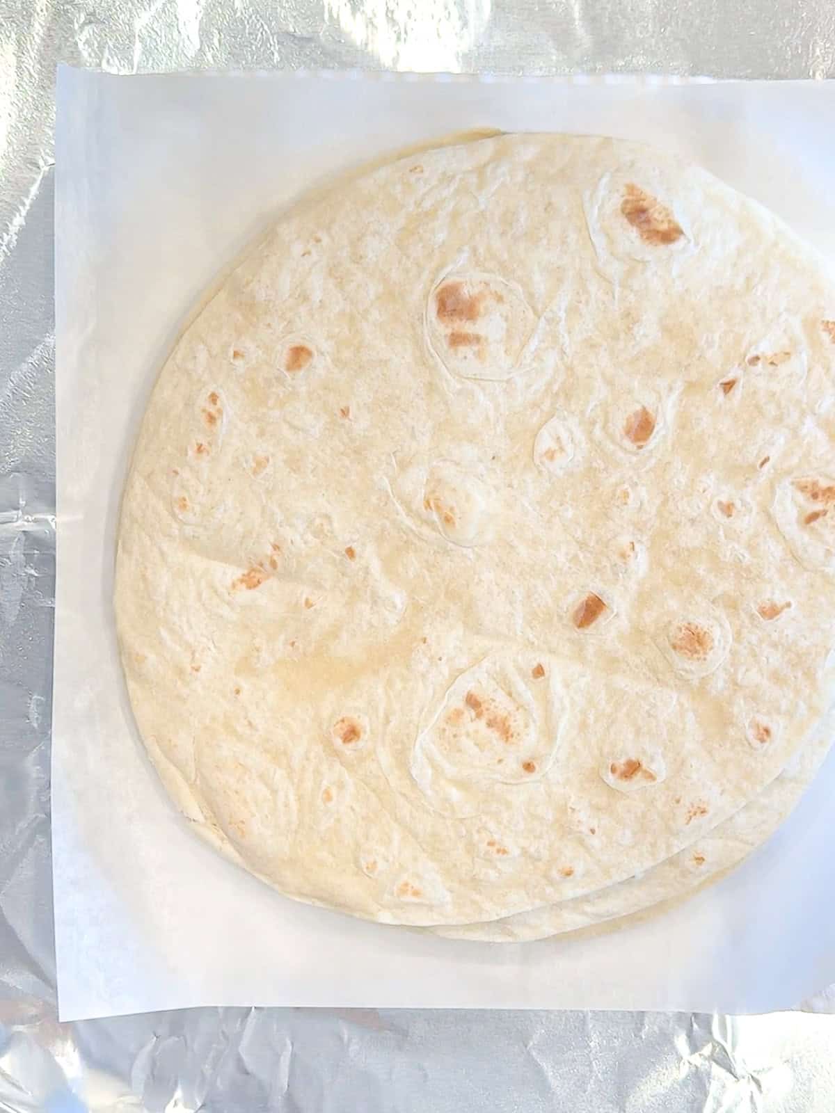 Wrapping tortillas in foil, damp towels, and parchment paper to warm up in the oven.