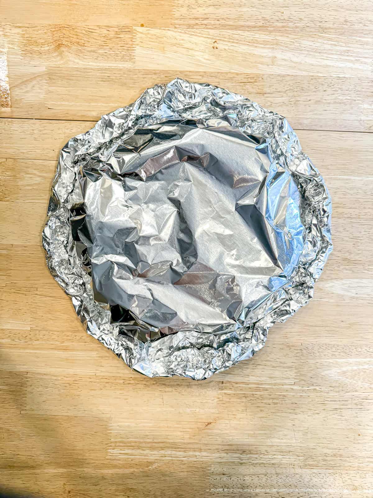 Tortillas completely encased in an aluminum foil packet for oven reheating.