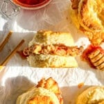 Side view of a fried chicken biscuit with spicy honey butter on parchment paper.