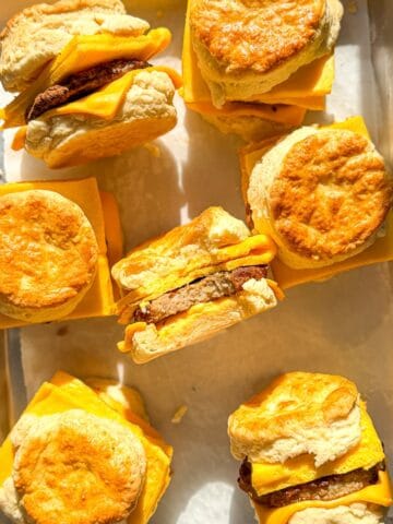 Sausage egg and cheese biscuits on a parchment paper lined sheet pan.
