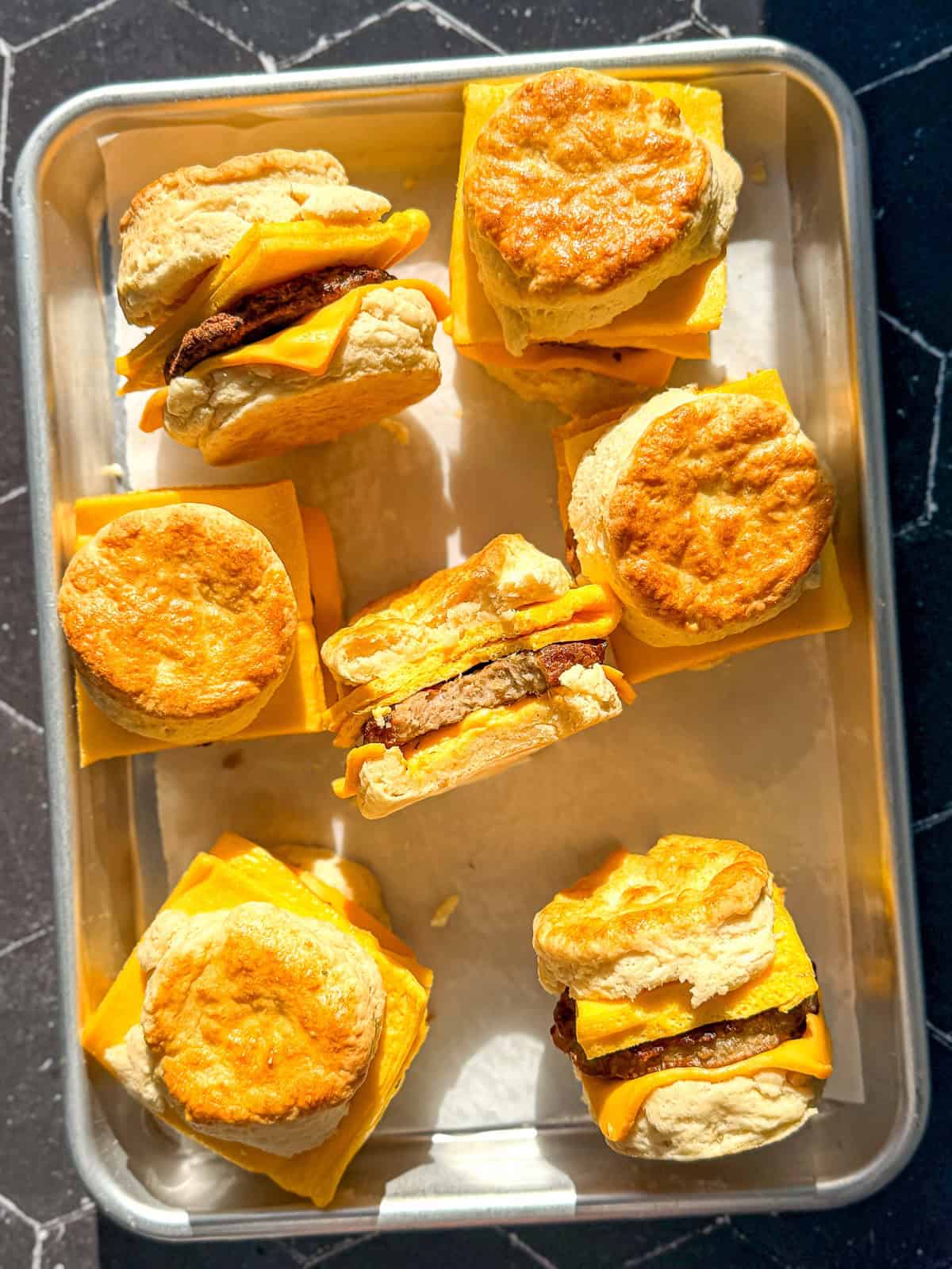 Sausage egg and cheese biscuits on a parchment paper lined sheet pan.