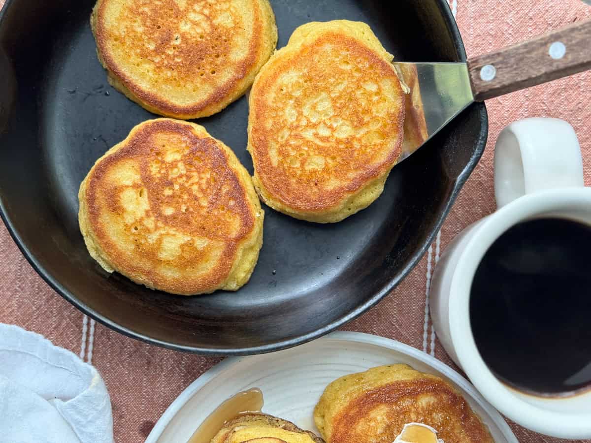 Southern hoecakes in a cast-iron pan with a cup of coffee next to it.