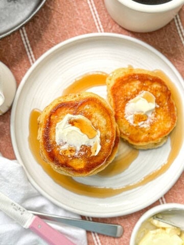 Southern hoecakes on a white plate with butter and maple syrup.