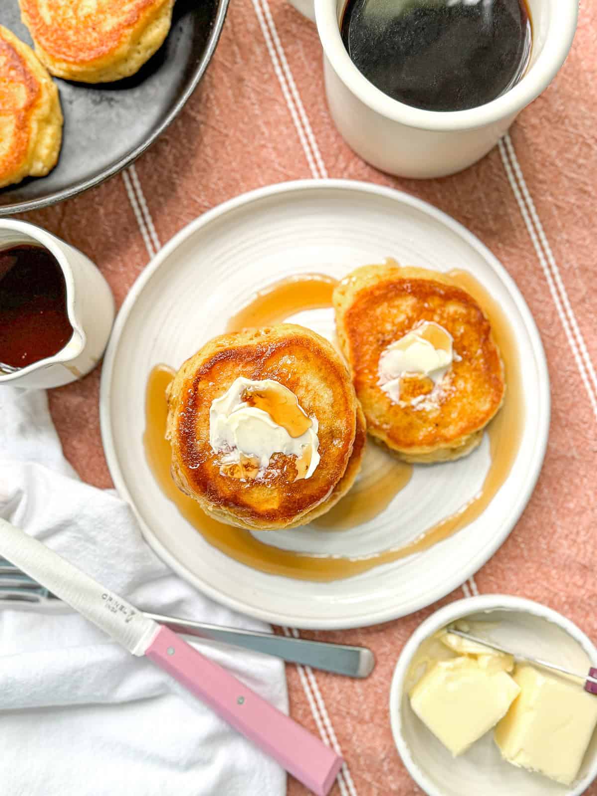 Southern hoecakes on a white plate with butter and maple syrup.