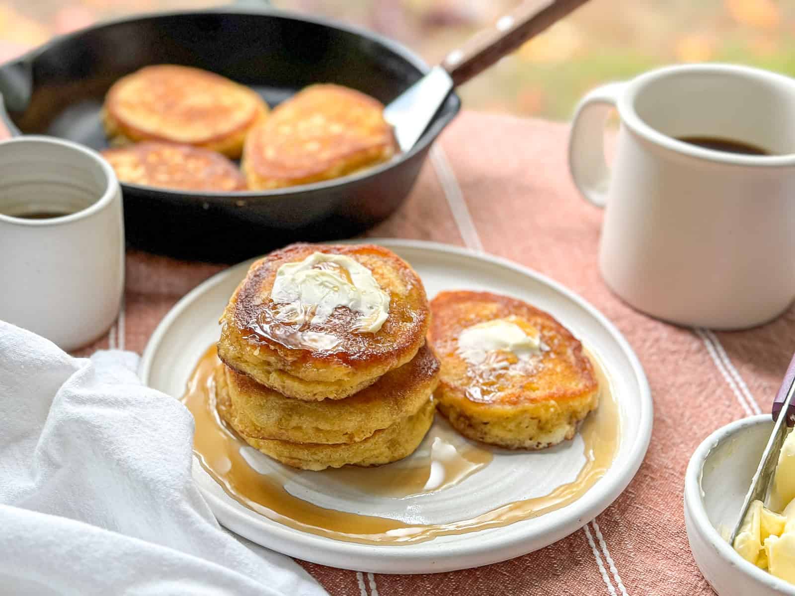 Southern hoecakes on a white plate with butter and maple syrup.