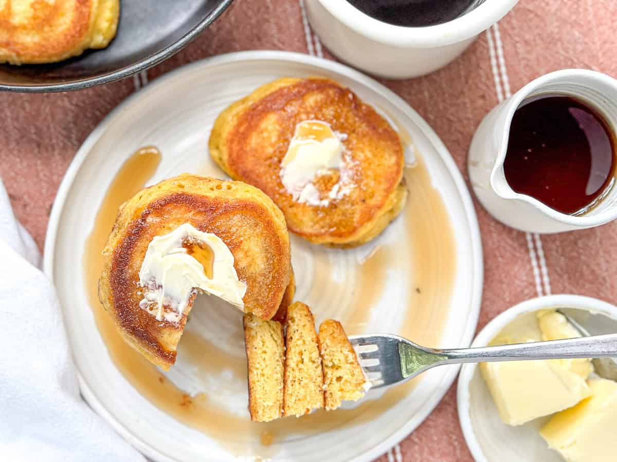 Southern hoecakes on a white plate with butter and maple syrup.