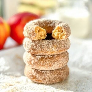 A stack of baked apple cider donuts, the one on top with a bite taken out.