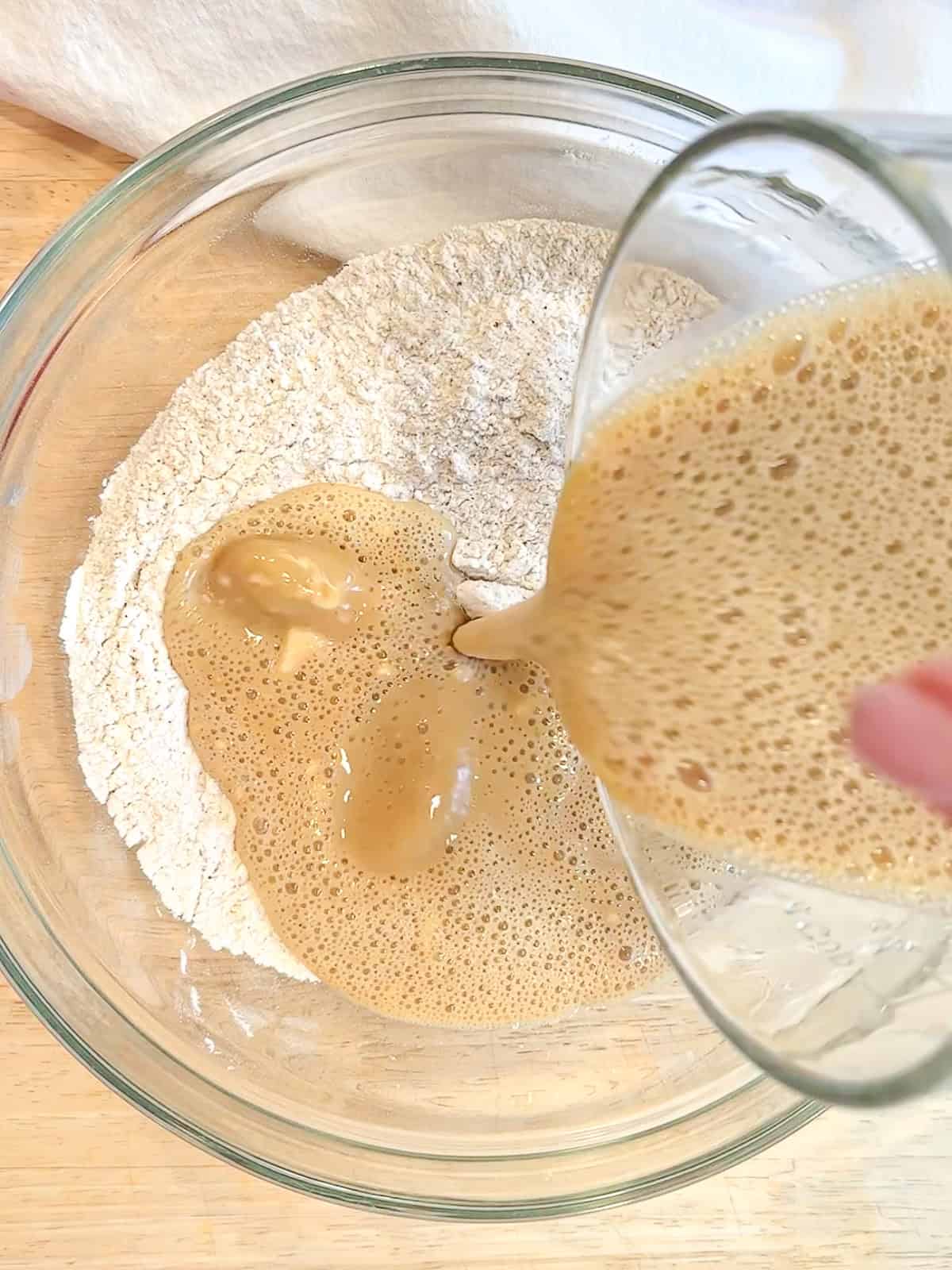 Adding ingredients into dry ingredients to make baked apple cider donut batter.