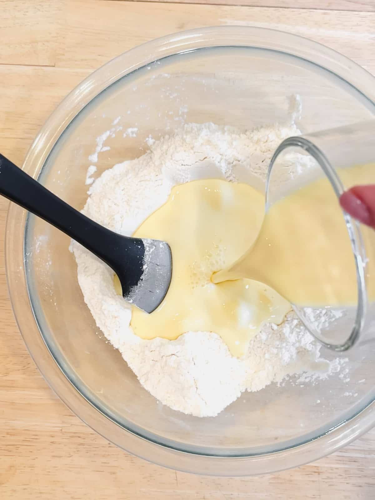 Adding wet ingredients into dry ingredients to make cinnamon roll pancake batter.