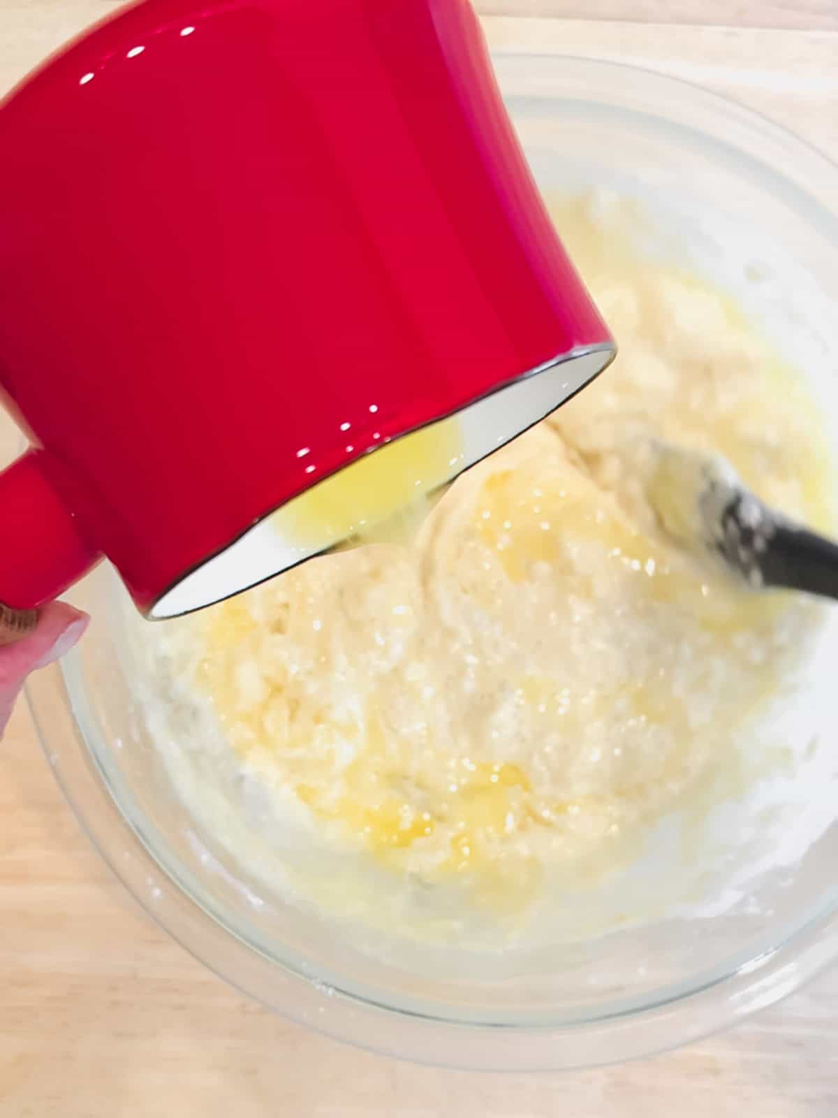 Adding melted and cooled butter to pancake batter.