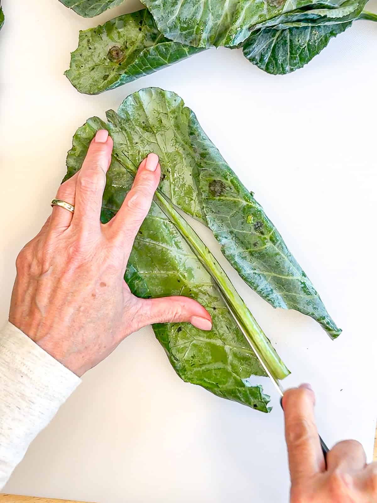 Slicing the stem out of a collard green leaf.