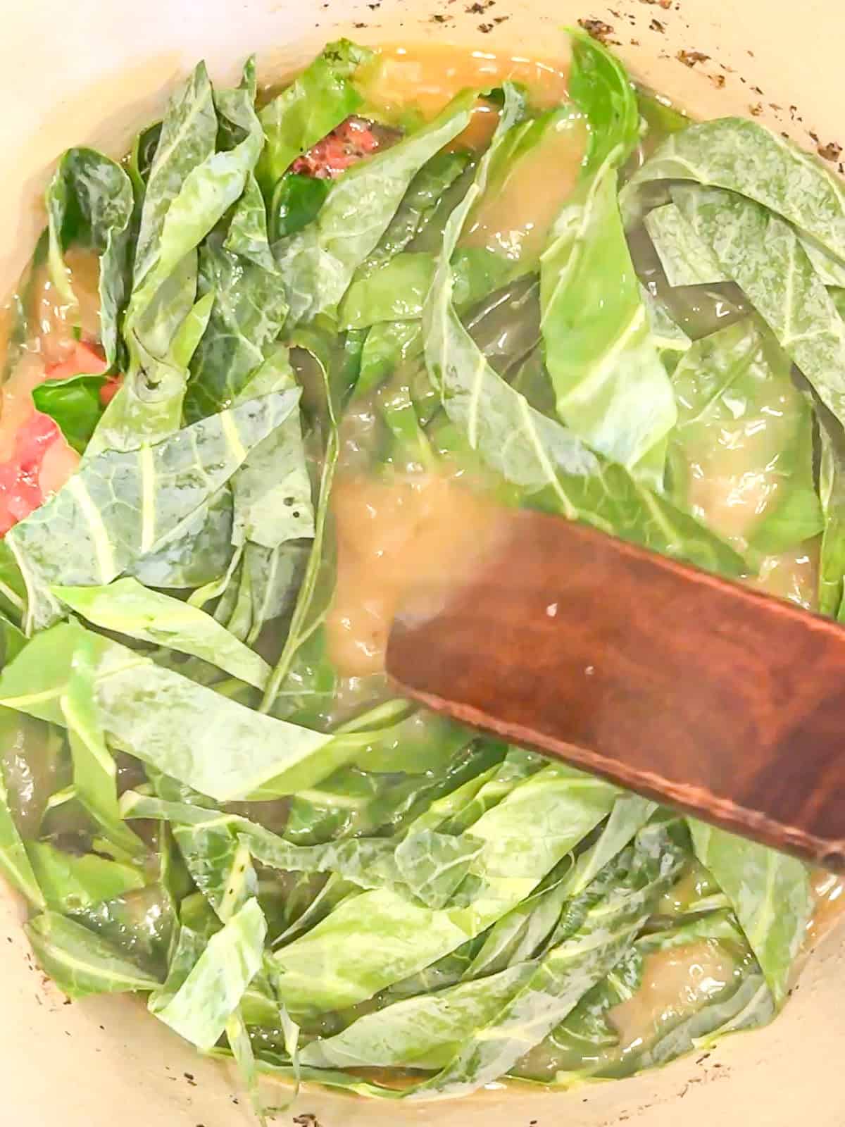 Adding collard greens to simmering pork stock.